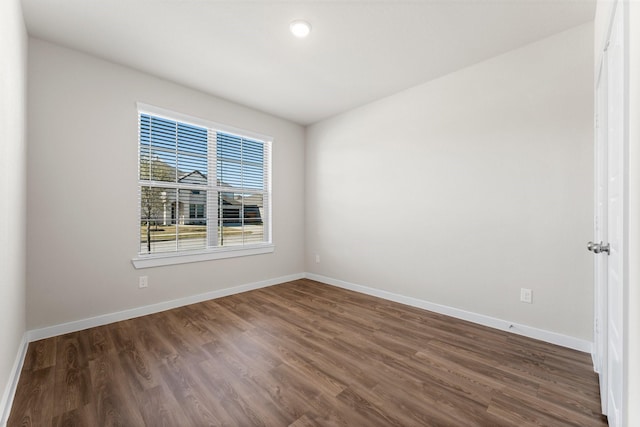 empty room with baseboards and dark wood-type flooring