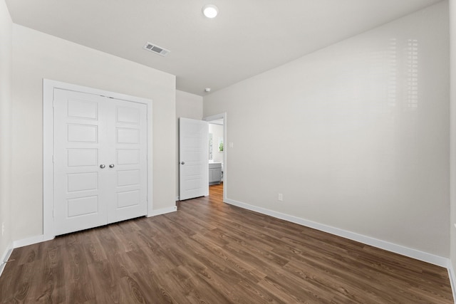 unfurnished bedroom with a closet, visible vents, dark wood finished floors, and baseboards