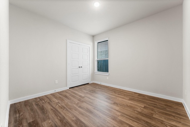 unfurnished room with baseboards and wood finished floors