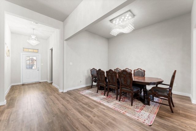 dining area featuring a notable chandelier, baseboards, and wood finished floors