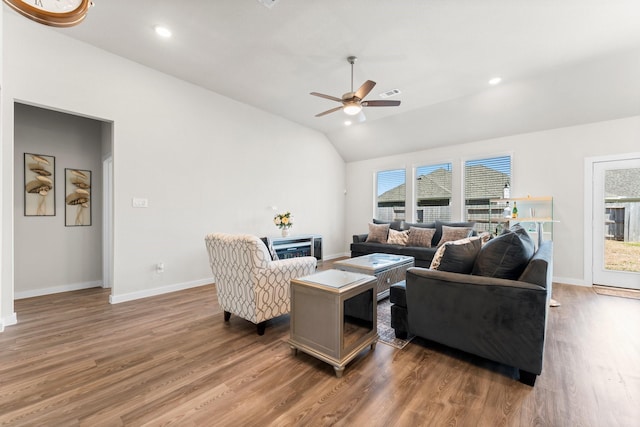 living area featuring vaulted ceiling, wood finished floors, and a healthy amount of sunlight