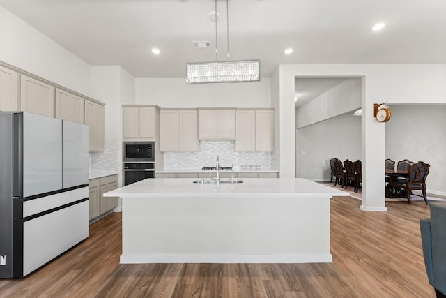 kitchen featuring oven, visible vents, light countertops, freestanding refrigerator, and stainless steel microwave