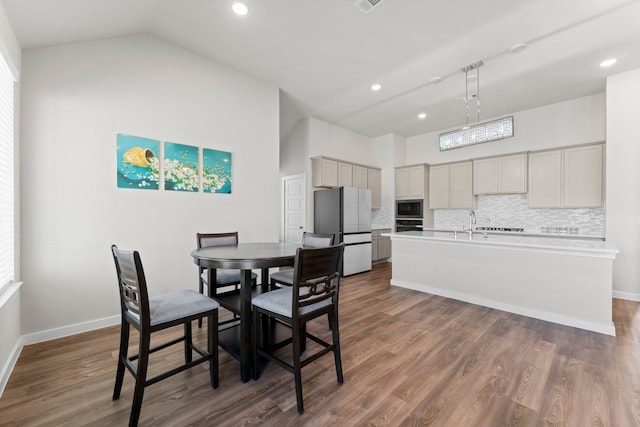 dining space featuring dark wood-style flooring, vaulted ceiling, and baseboards