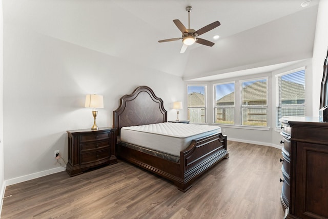 bedroom with vaulted ceiling, wood finished floors, and baseboards