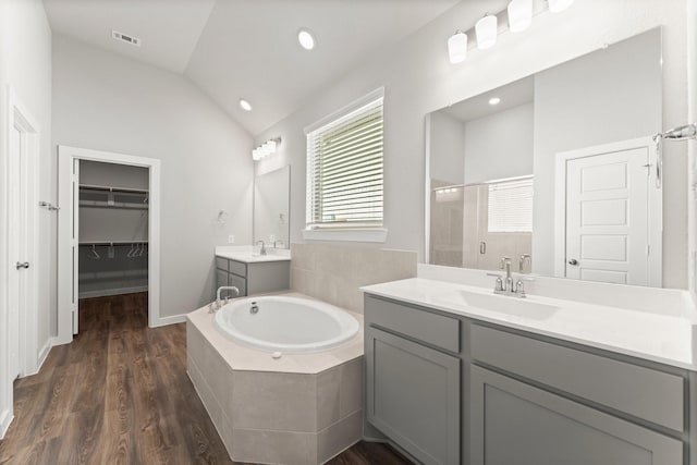 bathroom featuring lofted ceiling, a garden tub, wood finished floors, a sink, and a shower stall