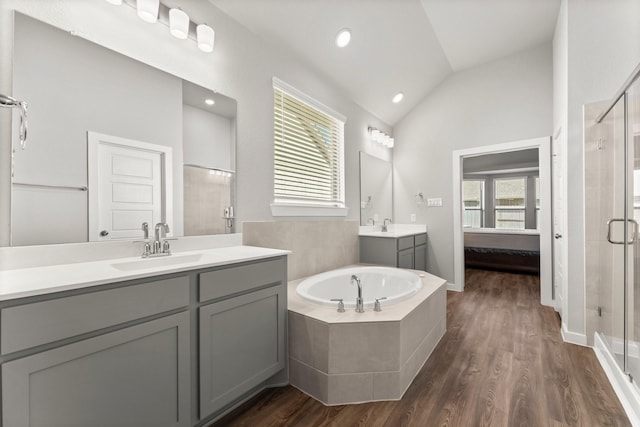 ensuite bathroom featuring a garden tub, vaulted ceiling, a shower stall, and wood finished floors