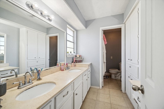 5502 Enchanted Timbers Dr, Humble, TX 77346 - bathroom with double vanity, healthy amount of natural light, tile patterned floors, and toilet