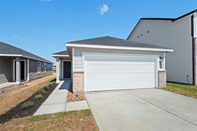 view of front of property featuring a garage, driveway, roof with shingles, and brick siding