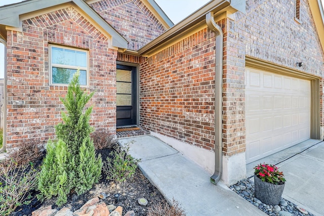 doorway to property featuring a garage and brick siding