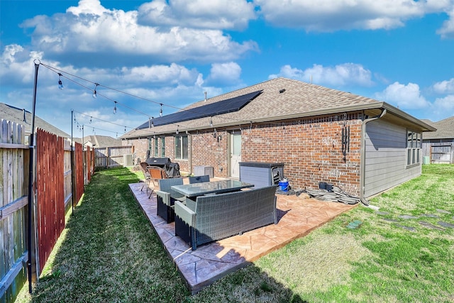 back of property featuring a fenced backyard, a yard, a patio area, an outdoor living space, and brick siding