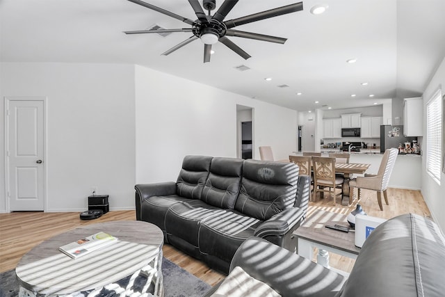 living room featuring light wood-type flooring, visible vents, and recessed lighting