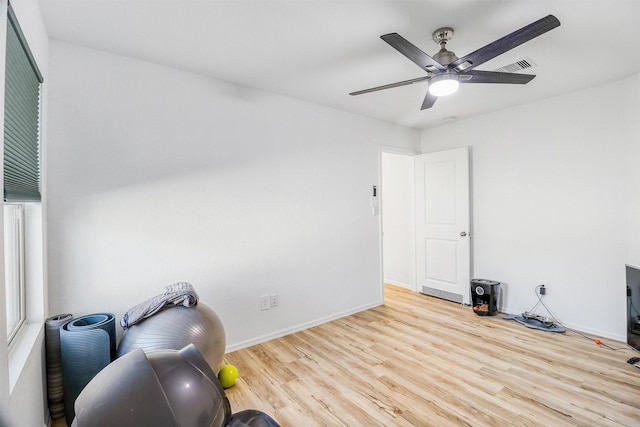 exercise room with baseboards, ceiling fan, visible vents, and wood finished floors