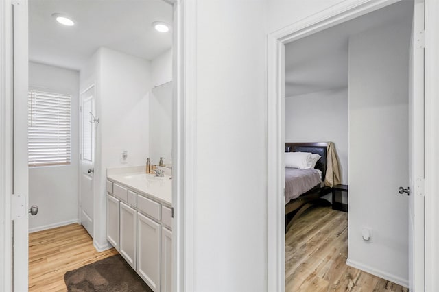 bathroom with recessed lighting, baseboards, wood finished floors, and vanity