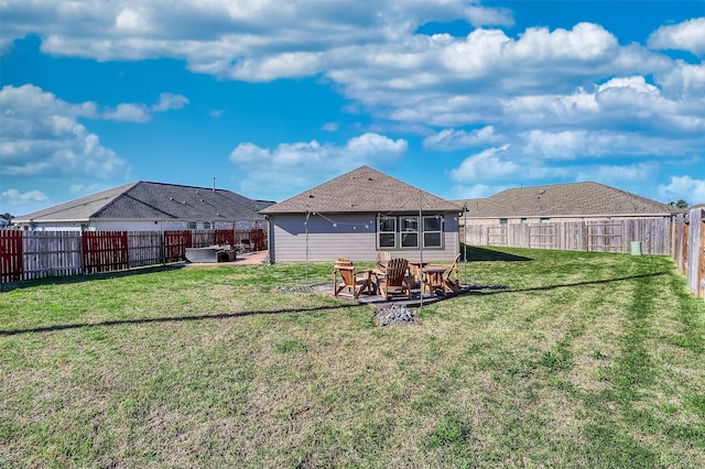 rear view of property featuring a yard, an outdoor fire pit, and a fenced backyard