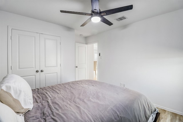 bedroom featuring ceiling fan, a closet, visible vents, and wood finished floors