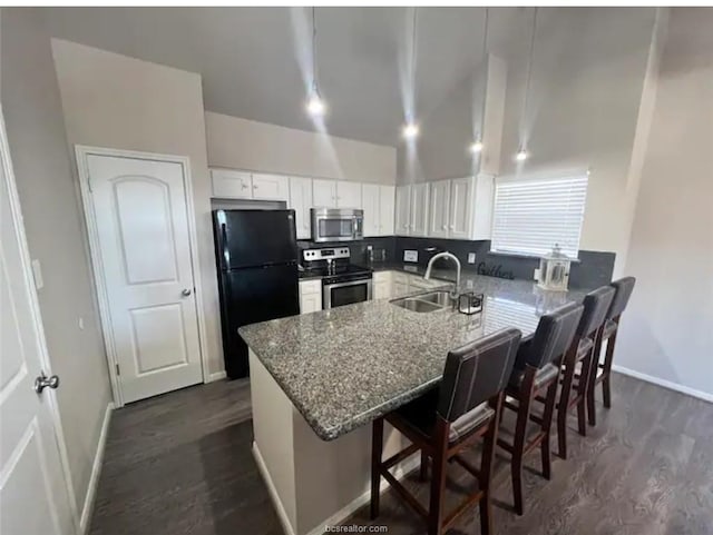 kitchen with dark wood-style floors, a peninsula, appliances with stainless steel finishes, and a sink