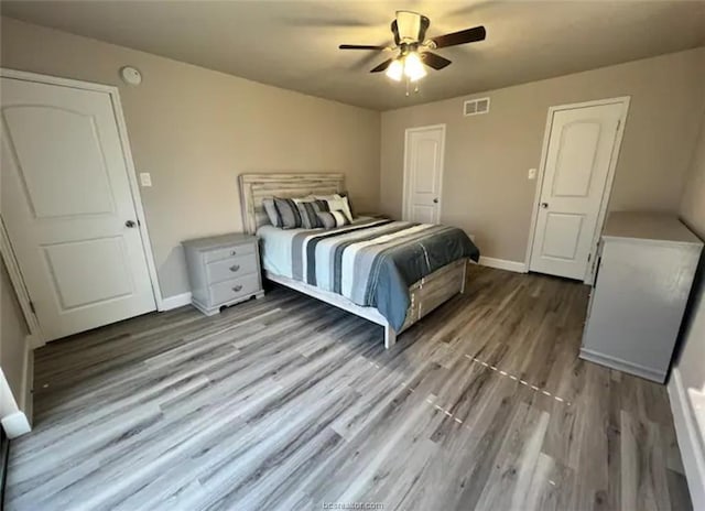 bedroom featuring a ceiling fan, baseboards, visible vents, and wood finished floors