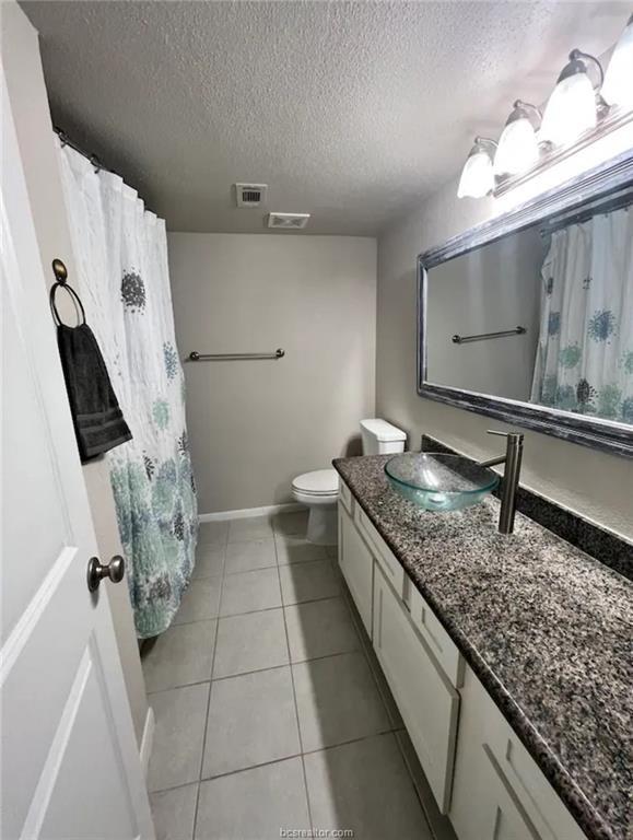 full bath featuring visible vents, toilet, a textured ceiling, vanity, and tile patterned flooring