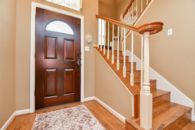 foyer featuring stairs, baseboards, and wood finished floors