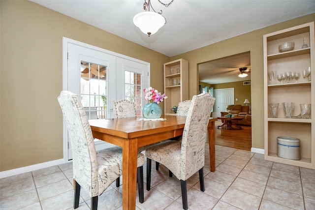 dining space with built in shelves, ceiling fan, baseboards, and light tile patterned floors