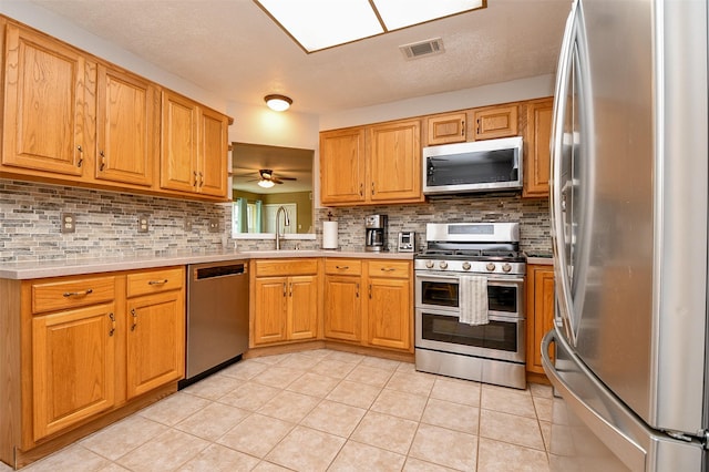 kitchen featuring tasteful backsplash, light countertops, visible vents, appliances with stainless steel finishes, and a sink