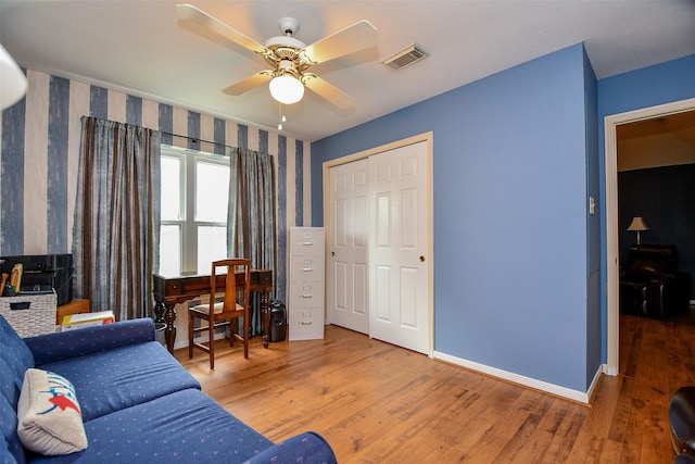 living area with a ceiling fan, visible vents, baseboards, and wood finished floors