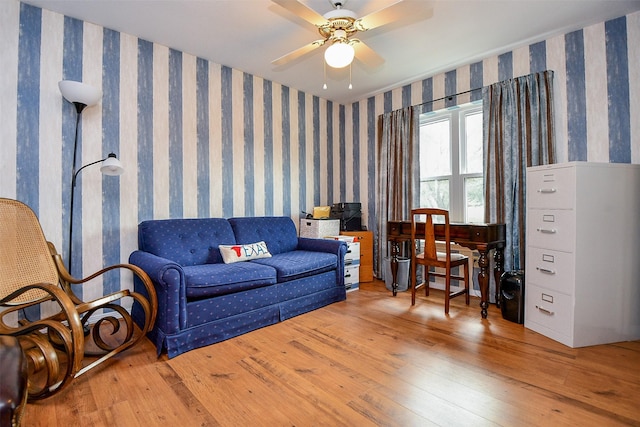 living room with hardwood / wood-style floors, a ceiling fan, and wallpapered walls