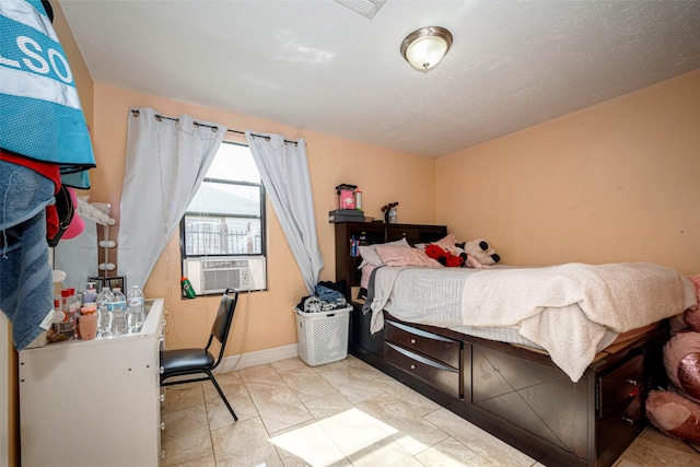 bedroom featuring cooling unit, a textured ceiling, and baseboards