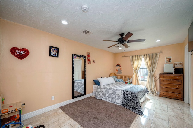 bedroom featuring a ceiling fan, visible vents, a textured ceiling, and baseboards