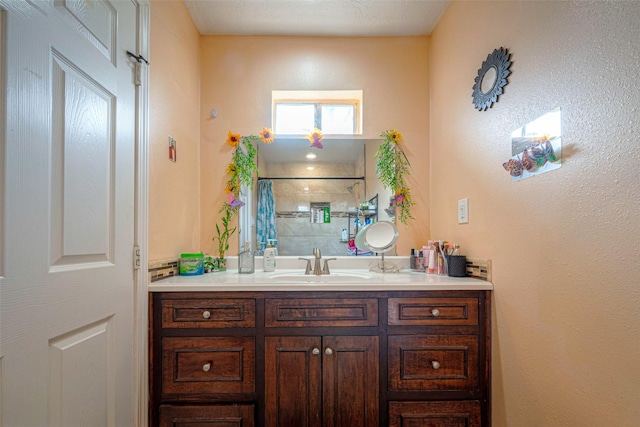 bathroom with a tile shower and vanity