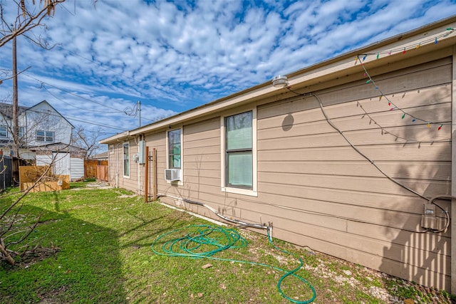 view of side of home with an outbuilding, cooling unit, fence, a lawn, and a storage unit