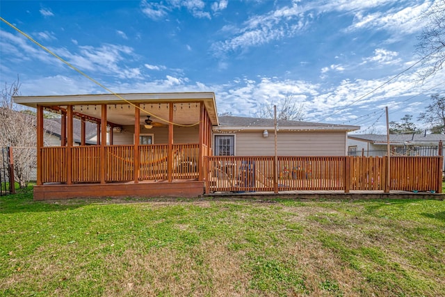 rear view of house featuring a deck, a lawn, fence, and a ceiling fan