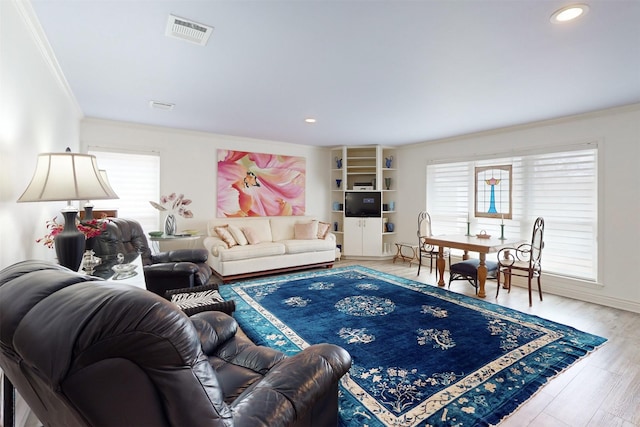 living area featuring plenty of natural light, visible vents, crown molding, and wood finished floors