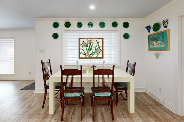 dining area featuring light wood-style flooring, baseboards, and ornamental molding