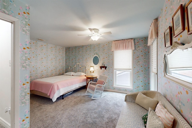 carpeted bedroom featuring wallpapered walls, ceiling fan, multiple windows, and visible vents
