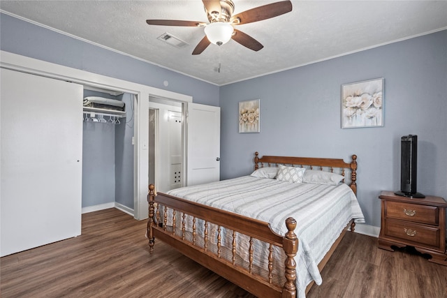 bedroom with a closet, visible vents, a textured ceiling, and wood finished floors