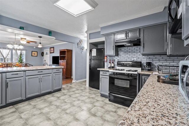 kitchen featuring crown molding, tasteful backsplash, gray cabinetry, under cabinet range hood, and black appliances