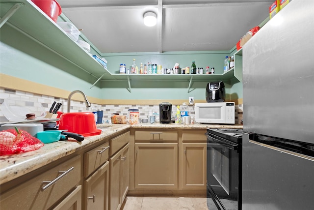 kitchen featuring tasteful backsplash, white microwave, black range with electric stovetop, freestanding refrigerator, and light countertops