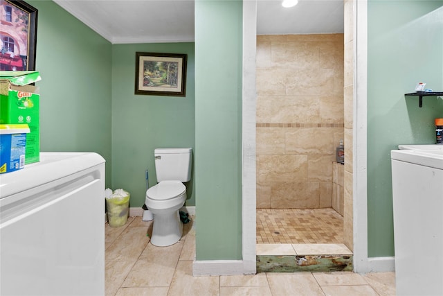 full bath featuring toilet, tile patterned flooring, a shower stall, washer and dryer, and baseboards