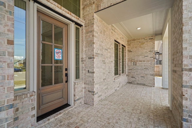 entrance to property featuring covered porch and brick siding