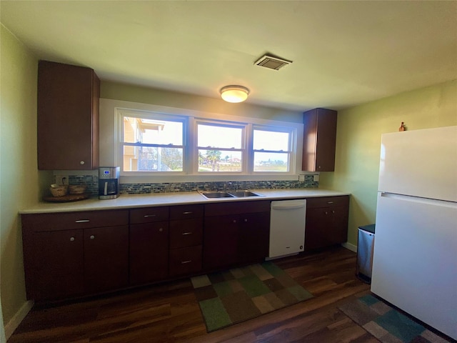 kitchen with white appliances, tasteful backsplash, visible vents, dark wood-style flooring, and a sink