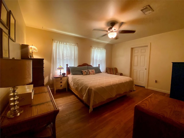 bedroom featuring a ceiling fan, wood finished floors, visible vents, and baseboards