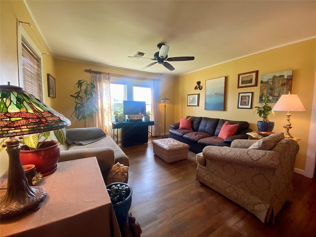 living area with a ceiling fan, dark wood-style flooring, visible vents, and crown molding