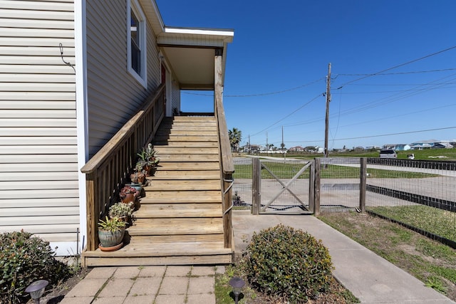 exterior space with a gate, fence, and stairway