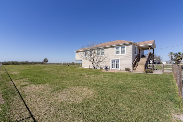 rear view of property with a fenced backyard, stairs, french doors, and a yard