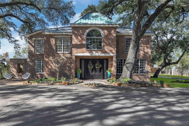 view of front of home featuring metal roof, brick siding, a standing seam roof, and french doors