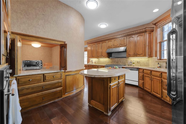 kitchen featuring under cabinet range hood, dark wood-style floors, light countertops, and dishwasher