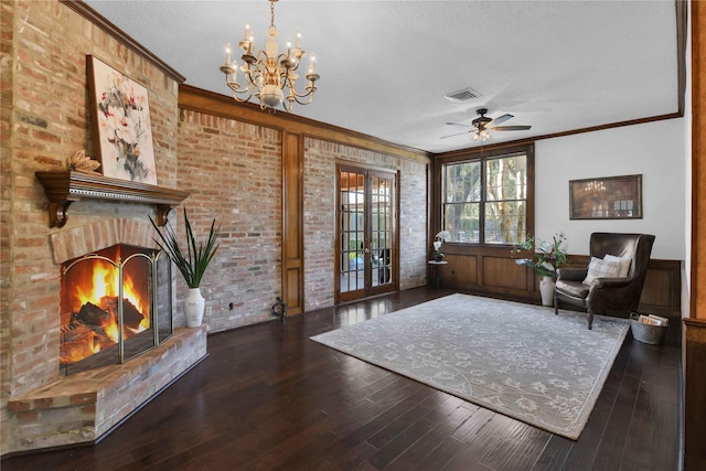 sitting room with brick wall, wood finished floors, visible vents, ornamental molding, and a brick fireplace