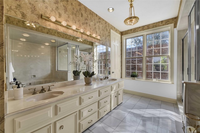 bathroom featuring baseboards, double vanity, a sink, and wallpapered walls