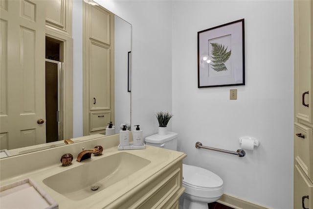 bathroom featuring a shower with shower door, vanity, and toilet